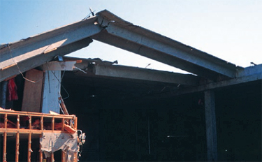 Photo of a precast twin-Tee roof where several of the roof and wall panels collapsed because of combined effects of wind uplift and pretension