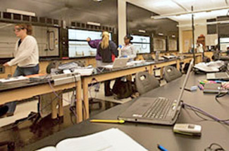 Movable tables in organic chemistry lab with open laptops on counters and students working in the background(Winona State University)