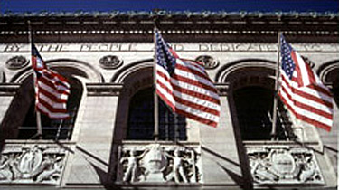Photo of a building facade with carned details and three American flags