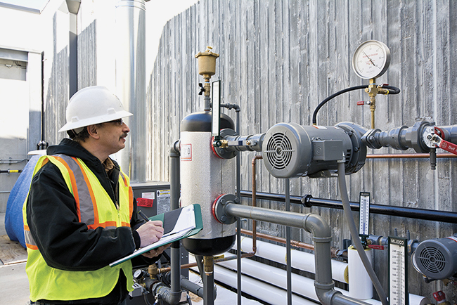 stock photo of worker in a hardhat and high viz vest examining equipment