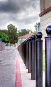 row of removable black bollards with a ball style top along roadway/sidewalk with red line road markings