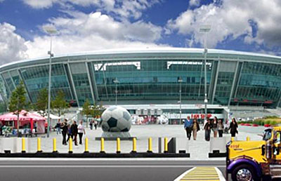 row of yellow surface mount bollards outside a sports stadium featuring soccer ball statue