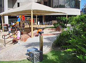 Children playing on the mulit-level play areas with sun shades overhead on a child development center playground in Hawaii
