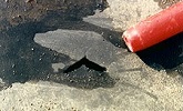 EPDM membrane cut by a piece of aggregate, the end of a pen shows the scale