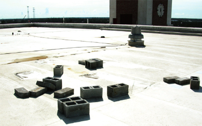 Photo of a satellite dish and support pan blown off a roof, only the CMU remains