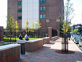 Large building complex with people sitting along knee wall vehicle barriers