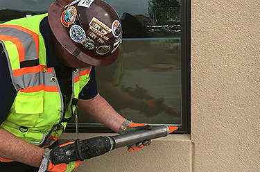 worker applying sealant to exterior of window