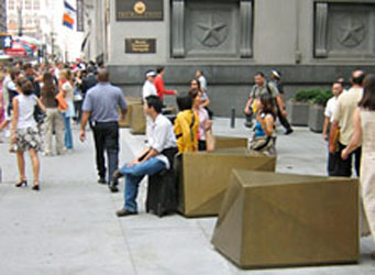 Sculptural bollards with people seated on them and pedestrains walking past in the Wall Street financial district