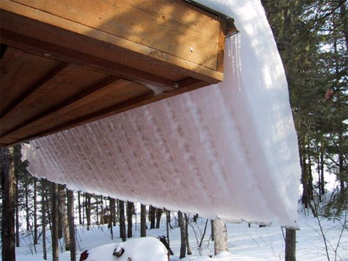 ice buildup on roof with snow and ice hanging over eaves