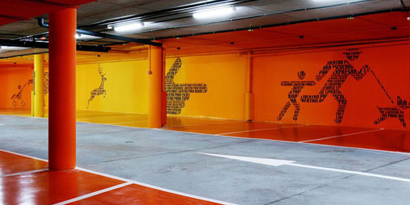 Underground parking at Hotel Puerta de América featuring directional bright murals along the walls