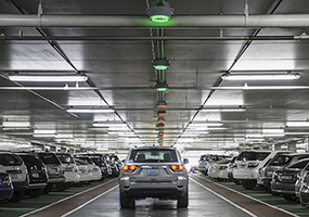 Parking garage with ceiling LED lights in red and green to display available parking spaces border=