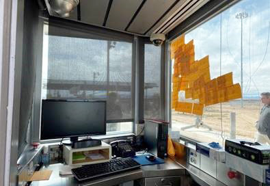 Office with two windows fitted with poorly fitted blinds and paper covering it to block sunlight