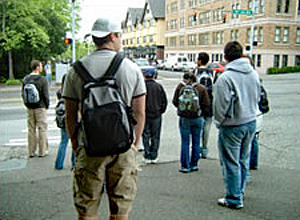 Comfort preferences are apparent in this picture that shows some people bundled up in hats and sweatshirts and others in shorts and tee shirts while waiting at a stop light.