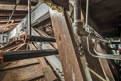 Attic of the Renwick Gallery, Smithsonian American Art Museum showing structural steel, fire protection piping, and electrical conduit threaded through the same plane as the original historic timbers