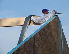 Worker installing SIP ridge and gable end tape/gasket seal.