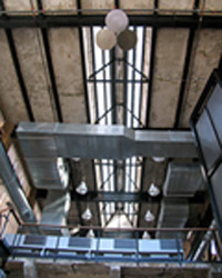 View looking up to the ceiling where one can see hvac ducts and the building's original monitor that runs along the length, the long sides of the monitor has louvers to light or ventilate the area under the roof.