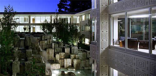 Photo of the exteriour of the Community Hospital of the Monterey Peninsula at night showing the unique landscaping or the lit rock garden, water feature and view