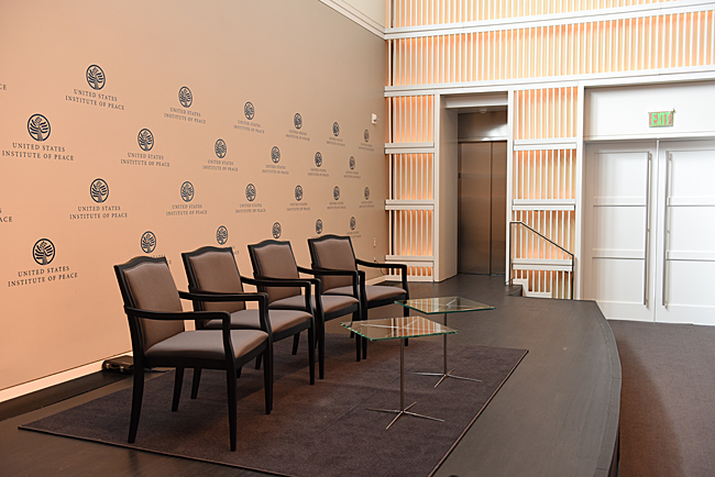 four chairs on a stage at the Institute of Peace with LULA elevator to the right of the stage